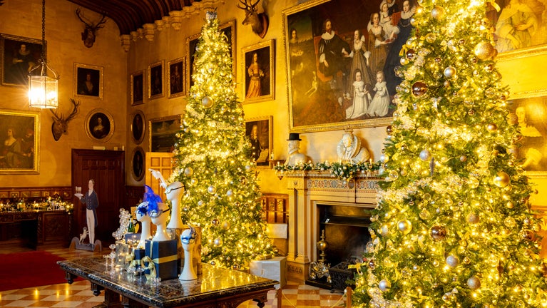 Two illuminated 16-ft Christmas trees flank a pietra dura table decorated with Venetian trees in Charlecote's Great Hall